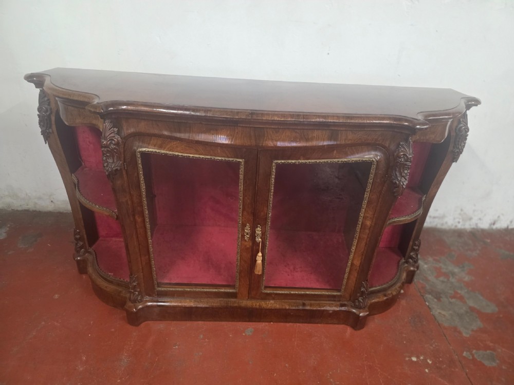 A Victorian rosewood credenza featuring central glazed double doors flanked by open curved side shelves with crimson fabric lining. View VI