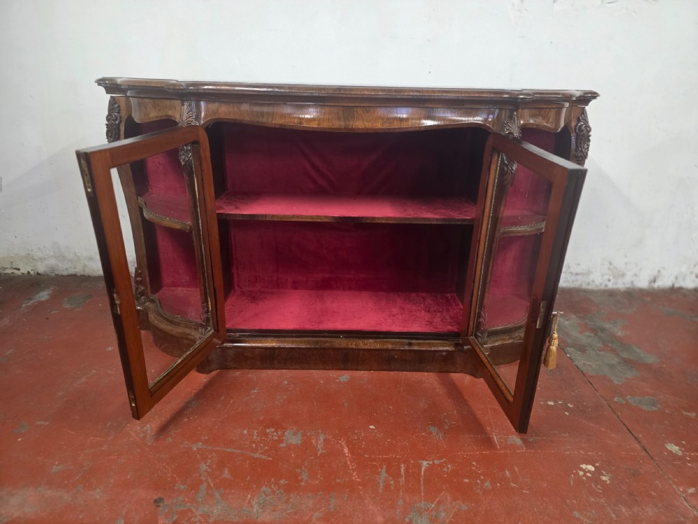 A Victorian rosewood credenza featuring central glazed double doors flanked by open curved side shelves with crimson fabric lining. View VIII