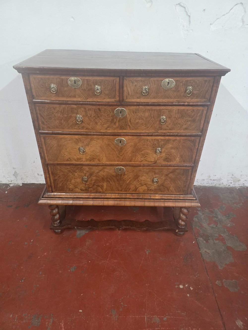 An early 18th-century Queen Anne burr walnut chest on stand featuring multiple graduated drawers with brass handles, resting on a base with barley twist legs and a shaped stretcher. View III