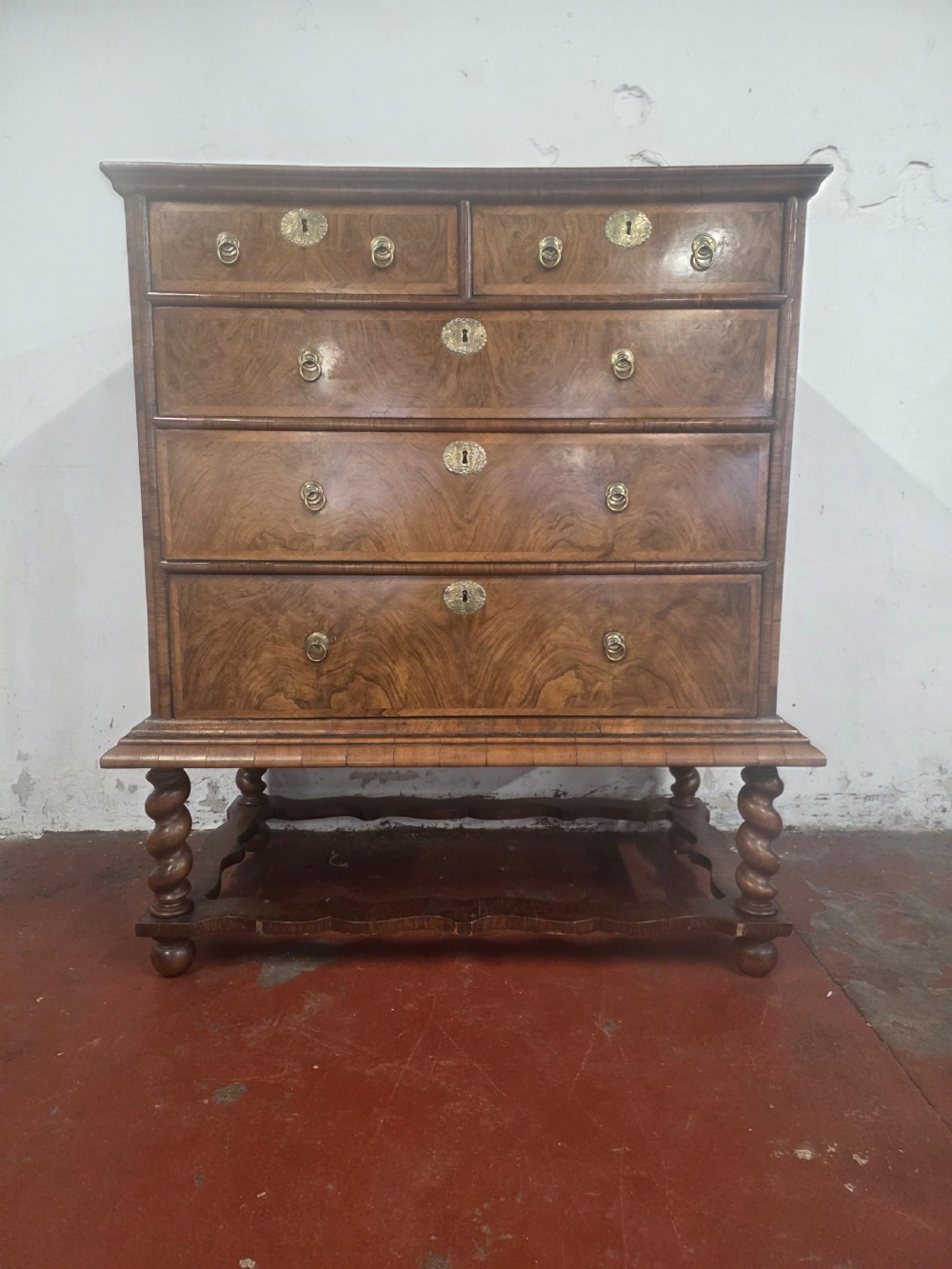 An early 18th-century Queen Anne burr walnut chest on stand featuring multiple graduated drawers with brass handles, resting on a base with barley twist legs and a shaped stretcher. View IV