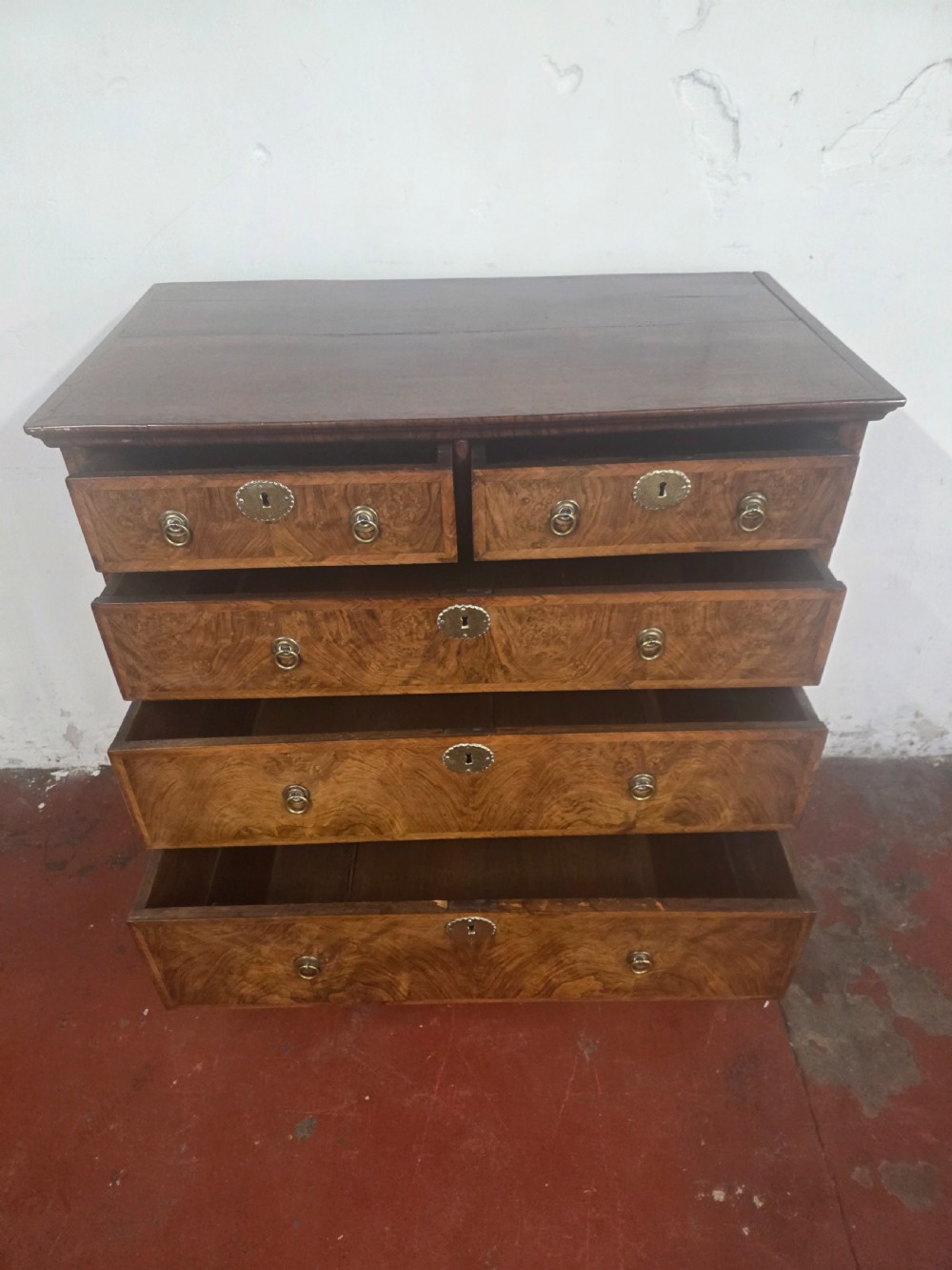 An early 18th-century Queen Anne burr walnut chest on stand featuring multiple graduated drawers with brass handles, resting on a base with barley twist legs and a shaped stretcher. View VII
