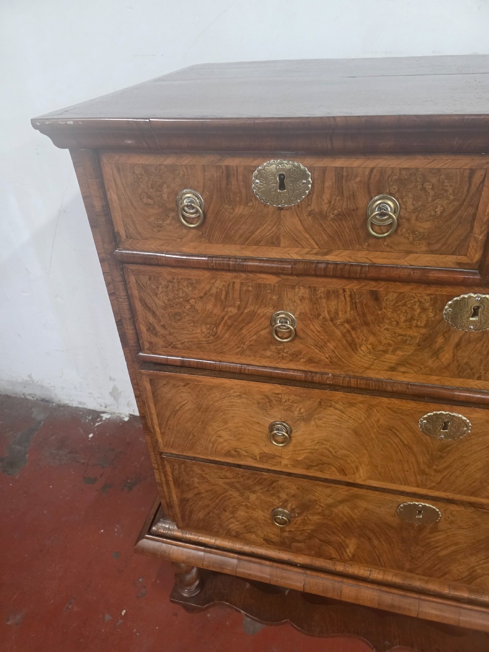An early 18th-century Queen Anne burr walnut chest on stand featuring multiple graduated drawers with brass handles, resting on a base with barley twist legs and a shaped stretcher. View VIII