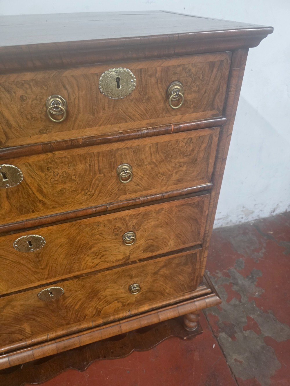 An early 18th-century Queen Anne burr walnut chest on stand featuring multiple graduated drawers with brass handles, resting on a base with barley twist legs and a shaped stretcher. View IX