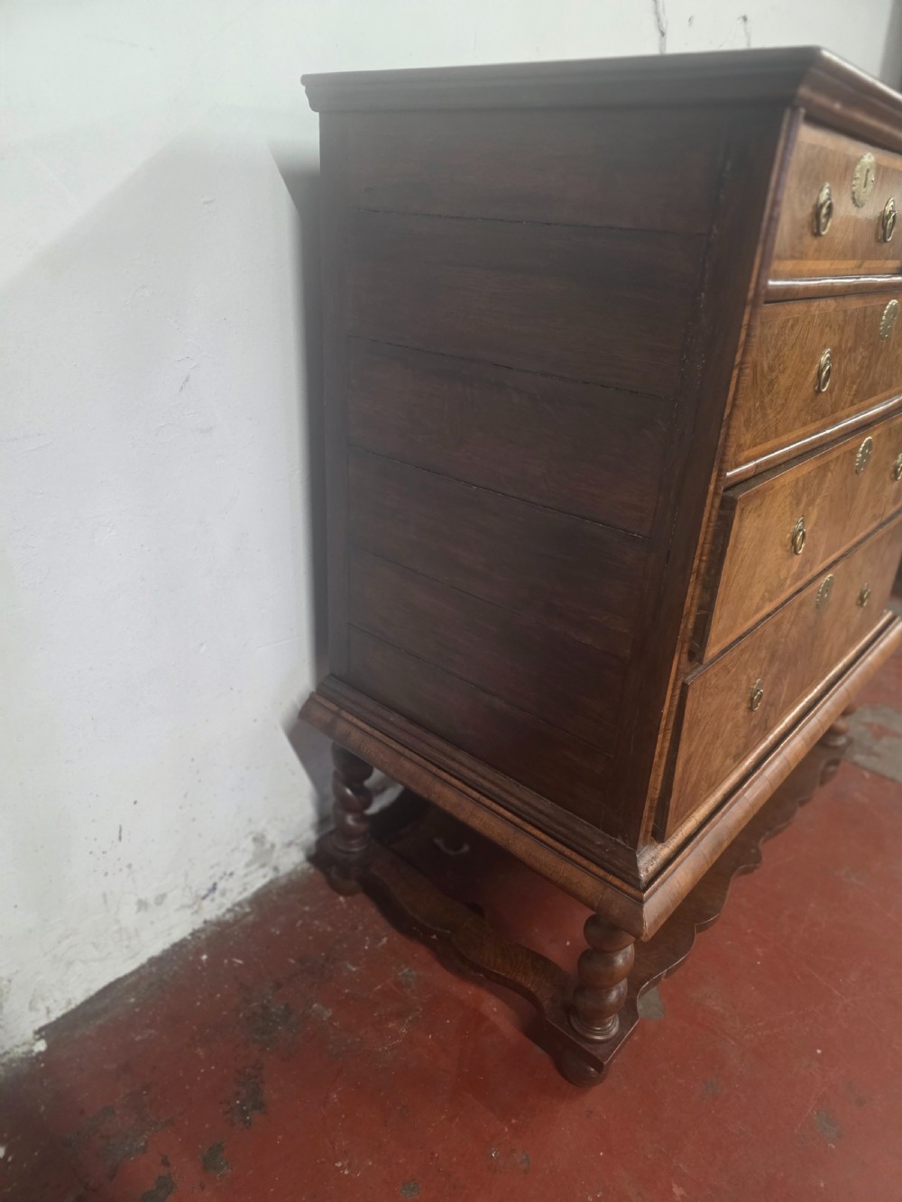 An early 18th-century Queen Anne burr walnut chest on stand featuring multiple graduated drawers with brass handles, resting on a base with barley twist legs and a shaped stretcher. View XI