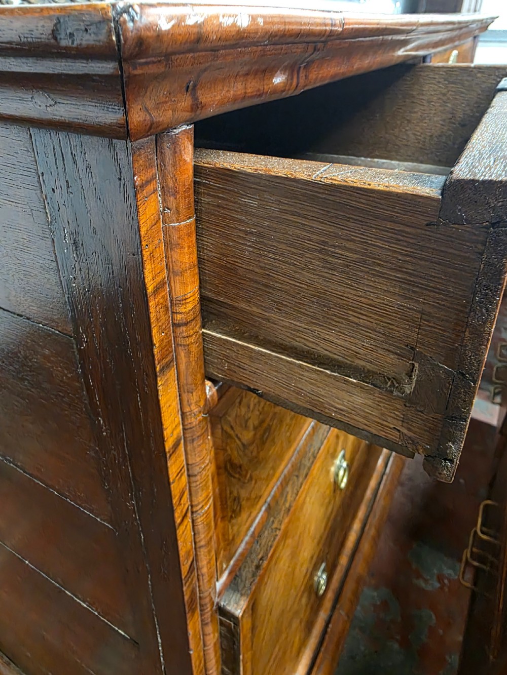 An early 18th-century Queen Anne burr walnut chest on stand featuring multiple graduated drawers with brass handles, resting on a base with barley twist legs and a shaped stretcher. View XV