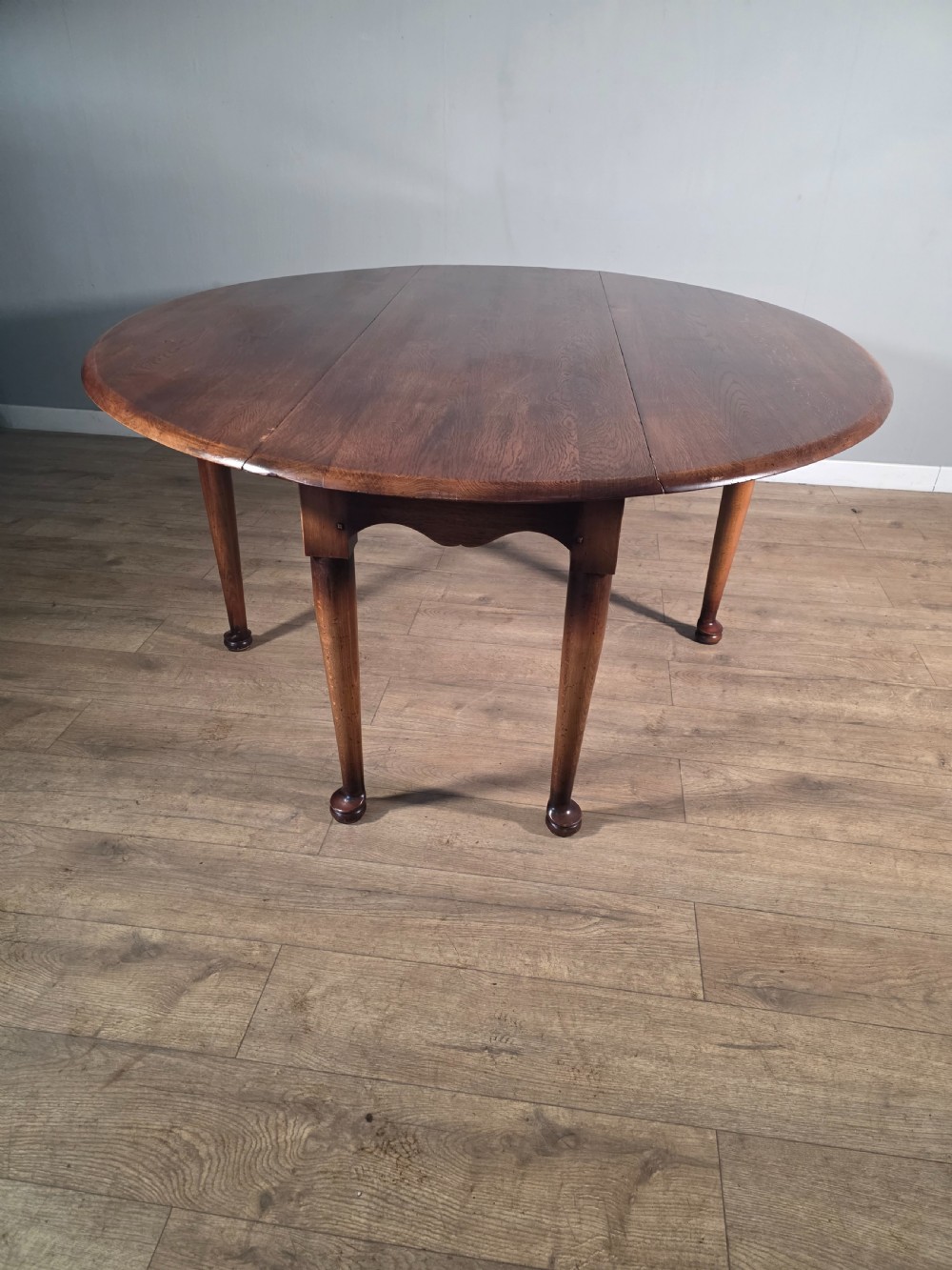 A large oval solid oak drop-leaf wake dining table featuring tapered legs with pad feet.