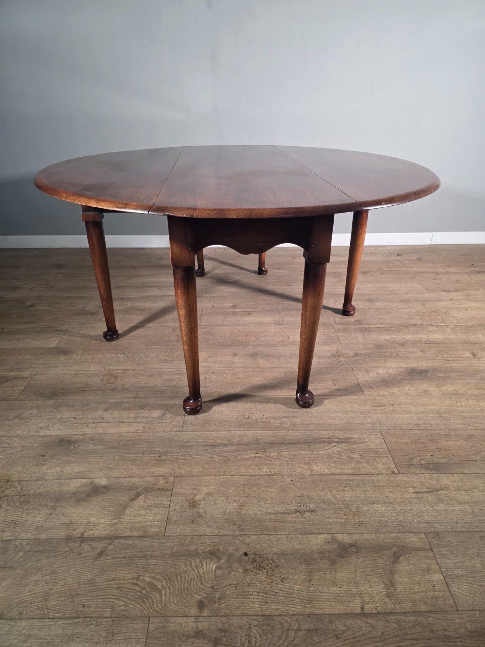 A large oval solid oak drop-leaf wake dining table featuring tapered legs with pad feet. View III