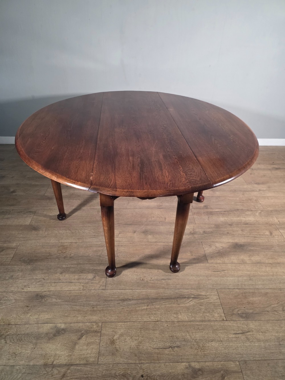 A large oval solid oak drop-leaf wake dining table featuring tapered legs with pad feet. View IV