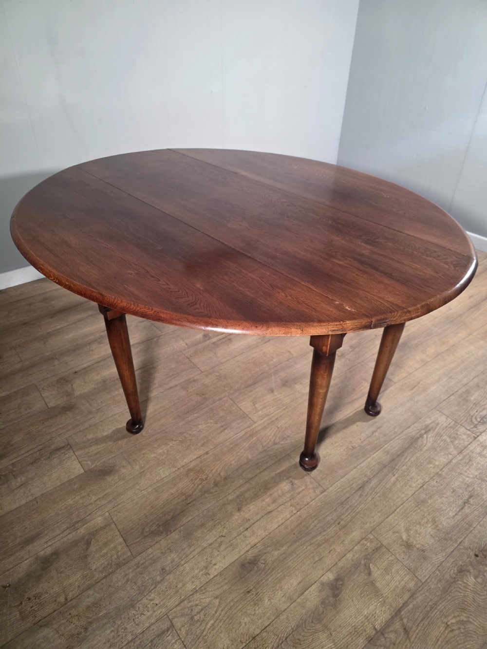 A large oval solid oak drop-leaf wake dining table featuring tapered legs with pad feet. View VII
