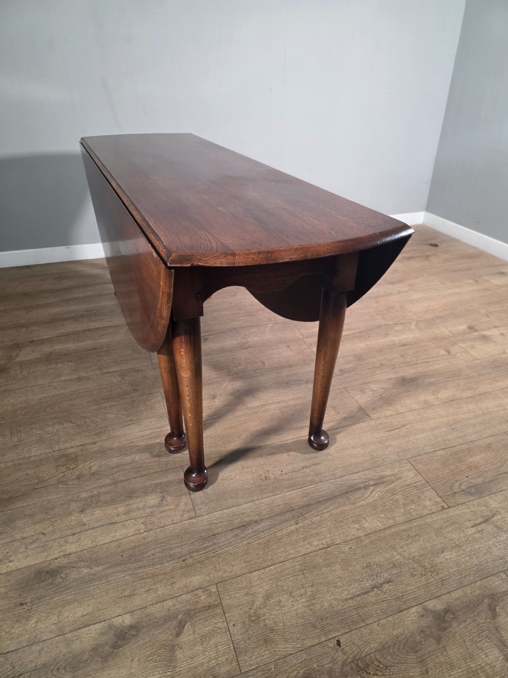 A large oval solid oak drop-leaf wake dining table featuring tapered legs with pad feet. View IX