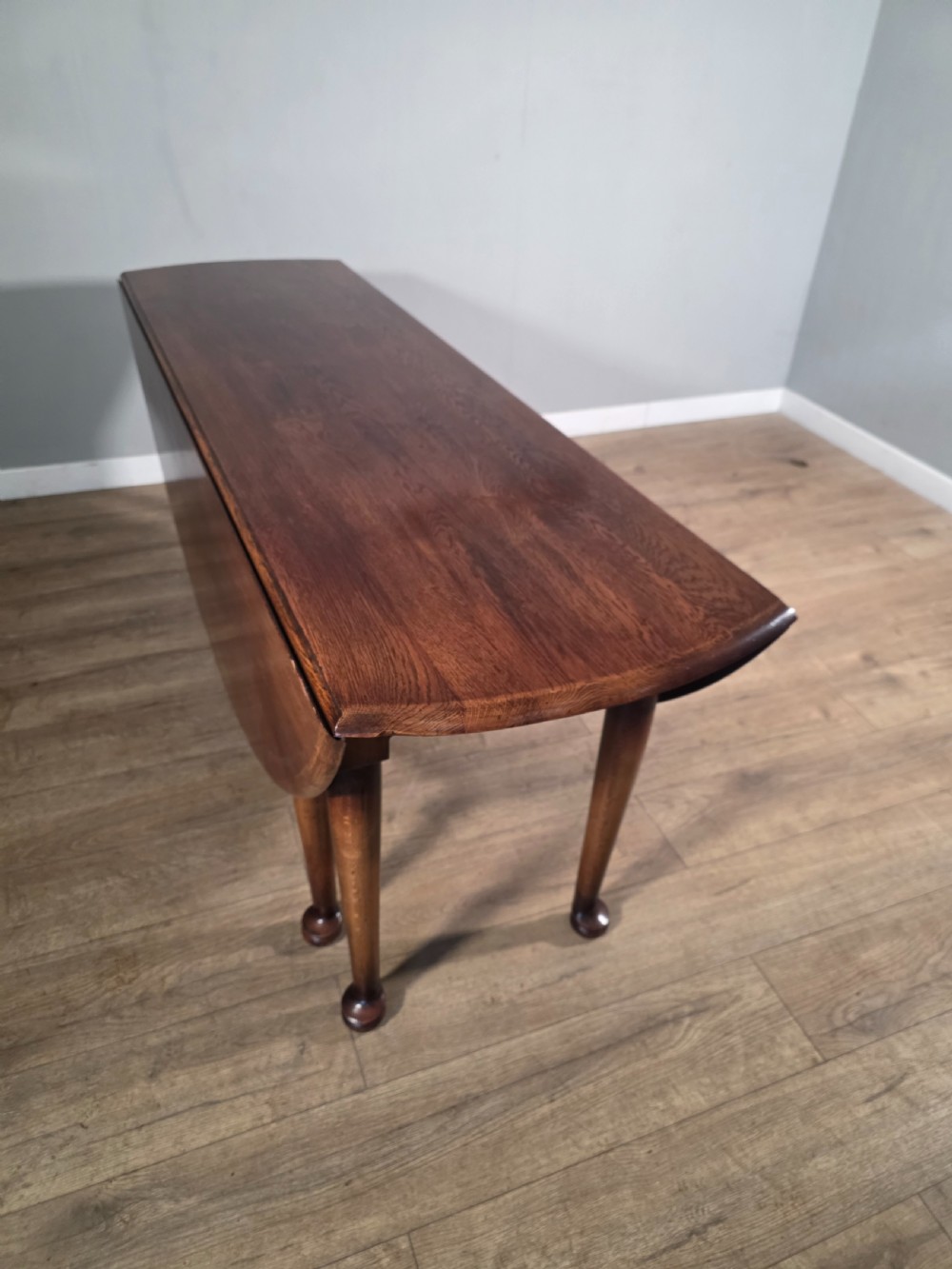 A large oval solid oak drop-leaf wake dining table featuring tapered legs with pad feet. View X