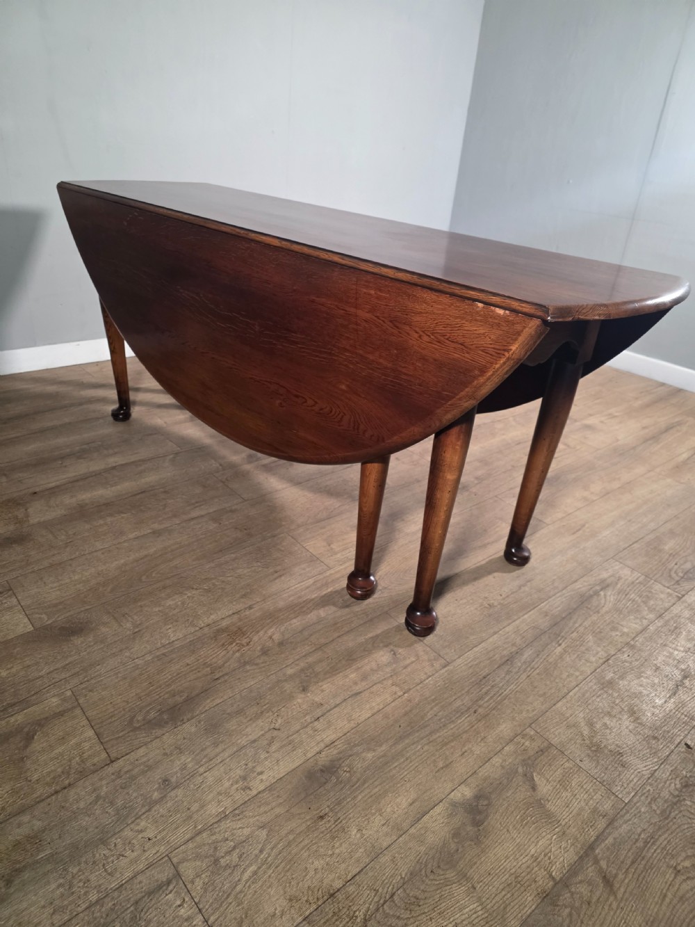 A large oval solid oak drop-leaf wake dining table featuring tapered legs with pad feet. View XI