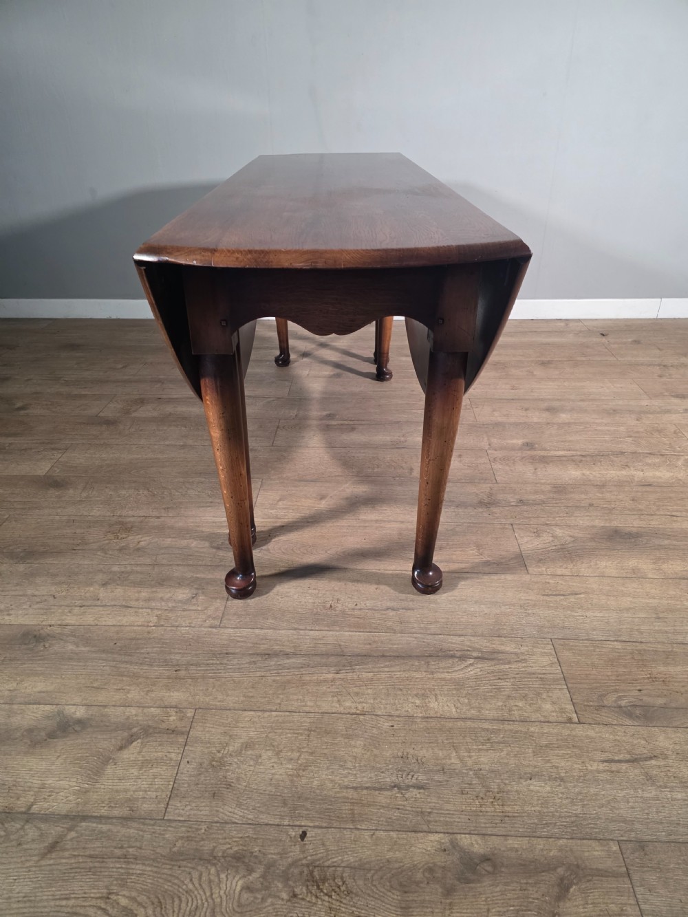 A large oval solid oak drop-leaf wake dining table featuring tapered legs with pad feet. View XII