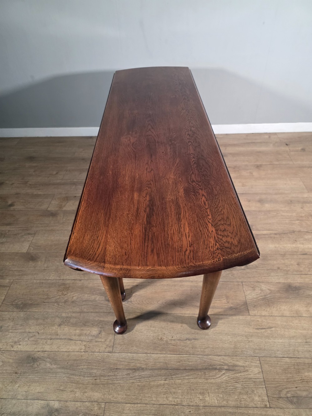 A large oval solid oak drop-leaf wake dining table featuring tapered legs with pad feet. View XIII
