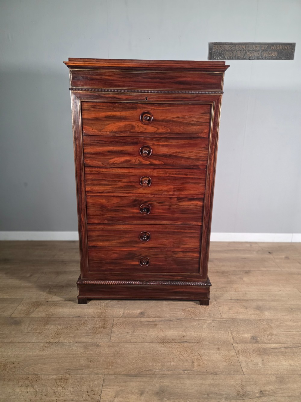 A tall 19th-century French rosewood chest featuring six drawers decorated with brass inlay stringing and turned wooden handles.