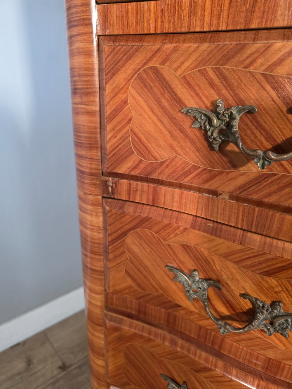 A tall 1930s French semainier chest featuring seven inlaid wood drawers, cast brass handles, a fitted brown marble top, and curved legs. View XVI
