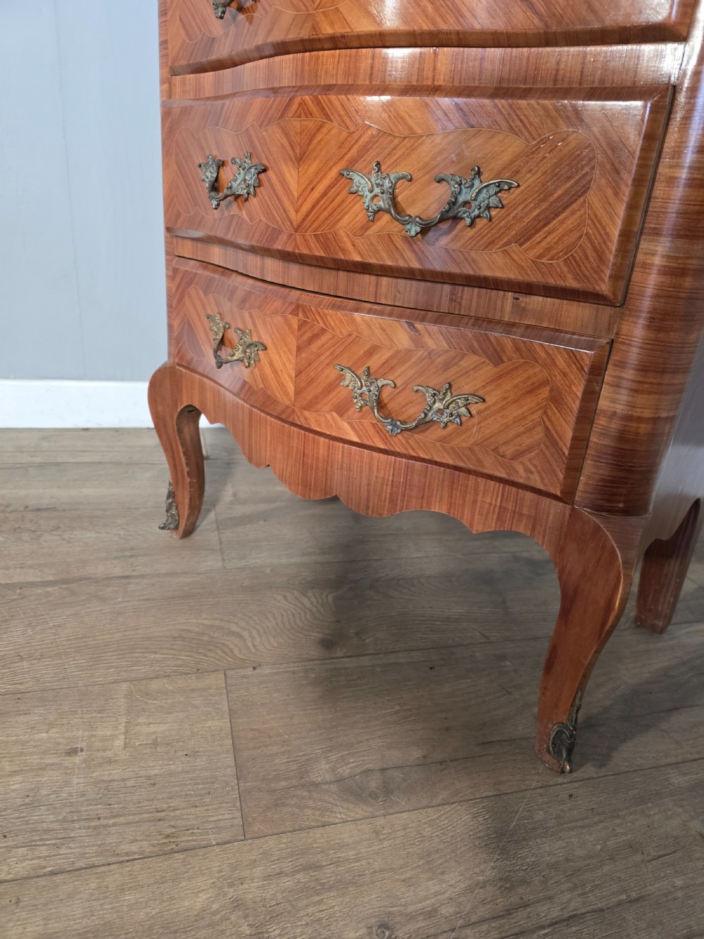 A tall 1930s French semainier chest featuring seven inlaid wood drawers, cast brass handles, a fitted brown marble top, and curved legs. View XVII