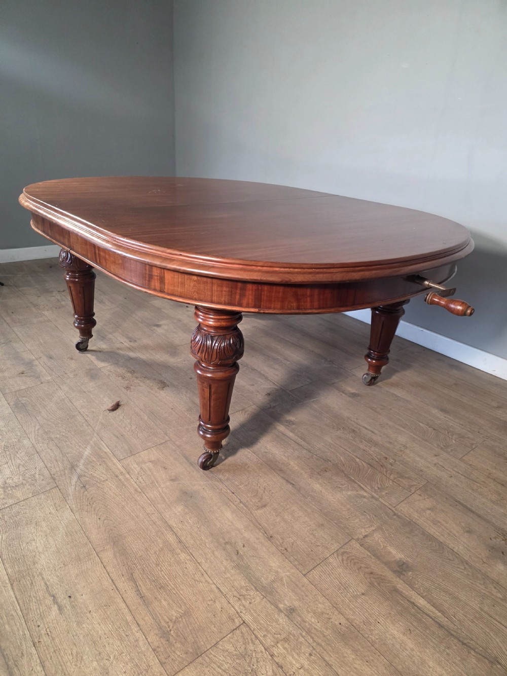 An antique Victorian mahogany extending dining table featuring an oval top, turned carved legs, and brass castors. View III