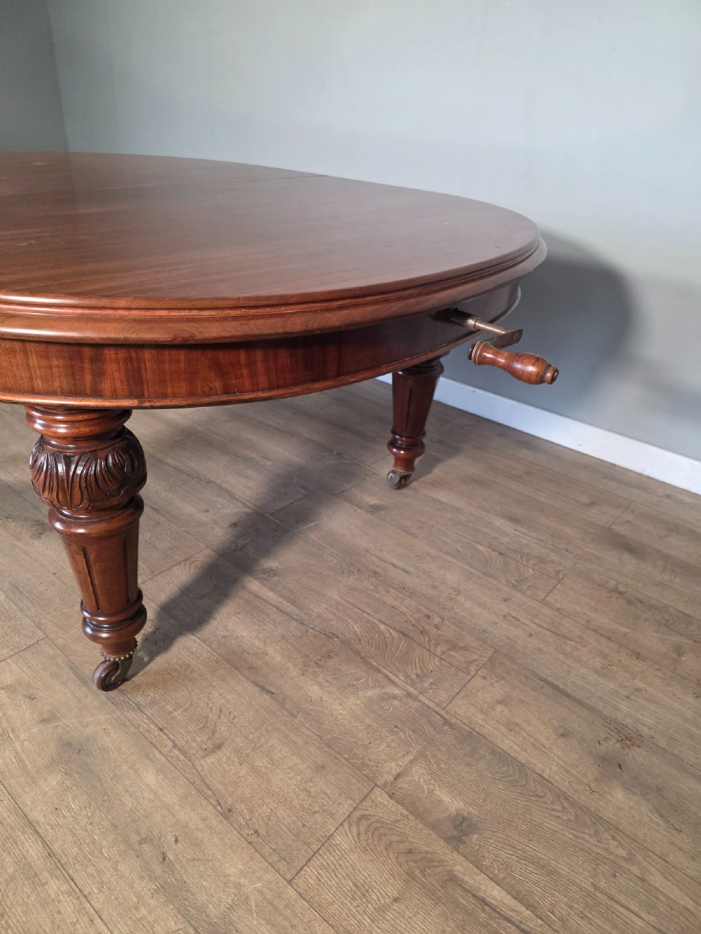 An antique Victorian mahogany extending dining table featuring an oval top, turned carved legs, and brass castors. View V