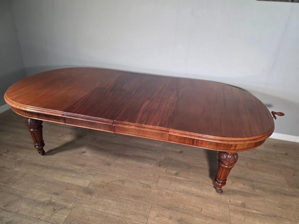 An antique Victorian mahogany extending dining table featuring an oval top, turned carved legs, and brass castors. View X