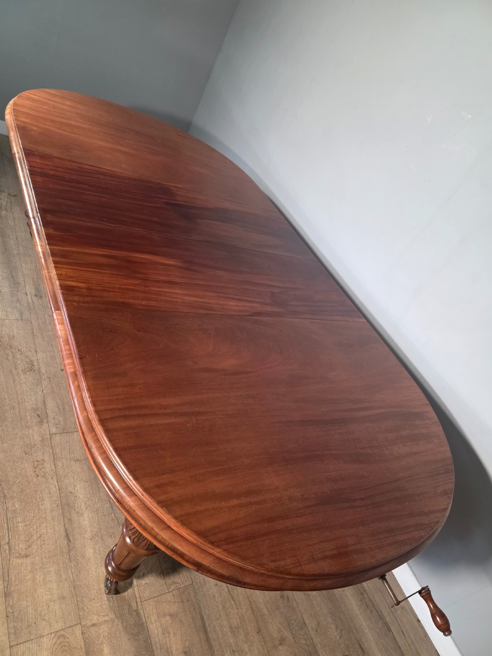 An antique Victorian mahogany extending dining table featuring an oval top, turned carved legs, and brass castors. View XI