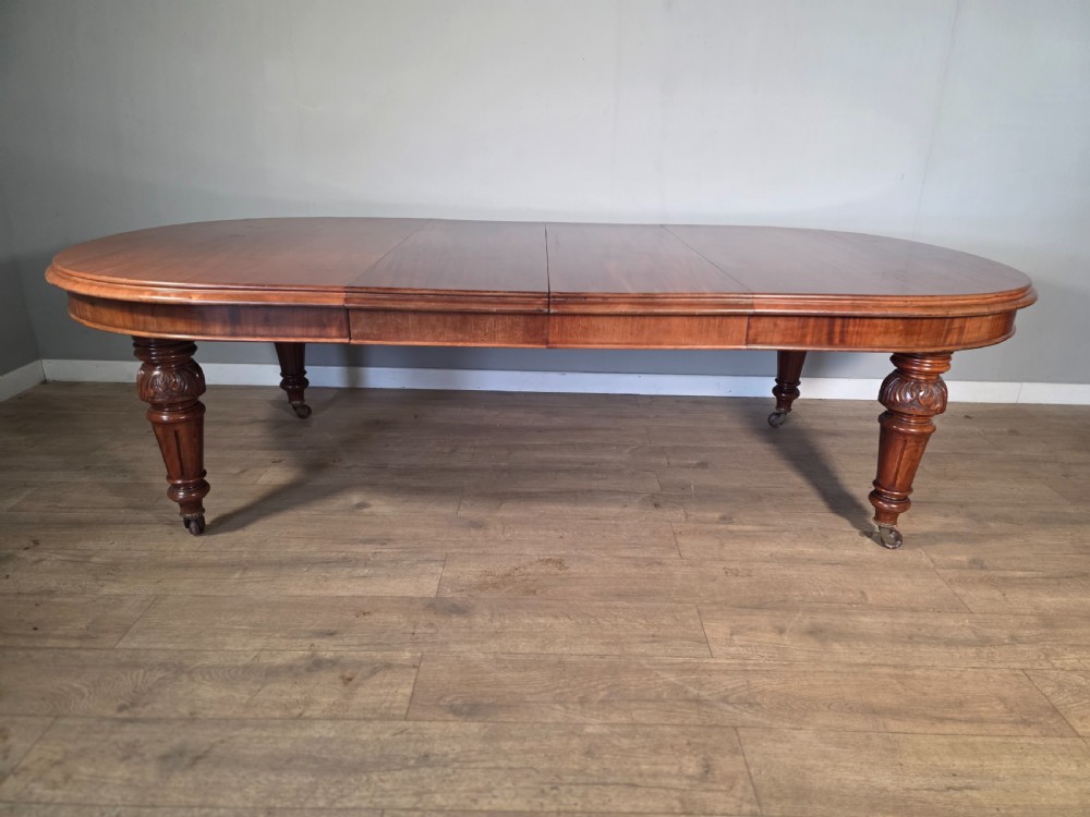 An antique Victorian mahogany extending dining table featuring an oval top, turned carved legs, and brass castors. View XII