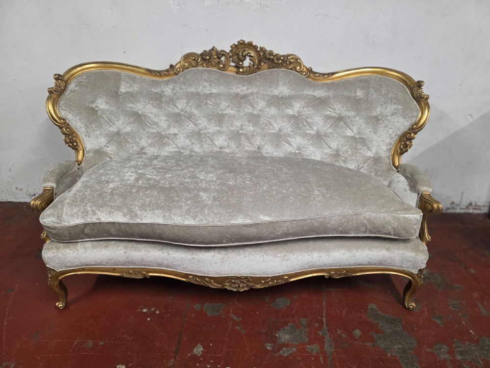 A late 19th-century Victorian Rococo Revival sofa with a carved gold giltwood frame, deep button-tufted light grey velvet backrest, and cabriole legs. View III