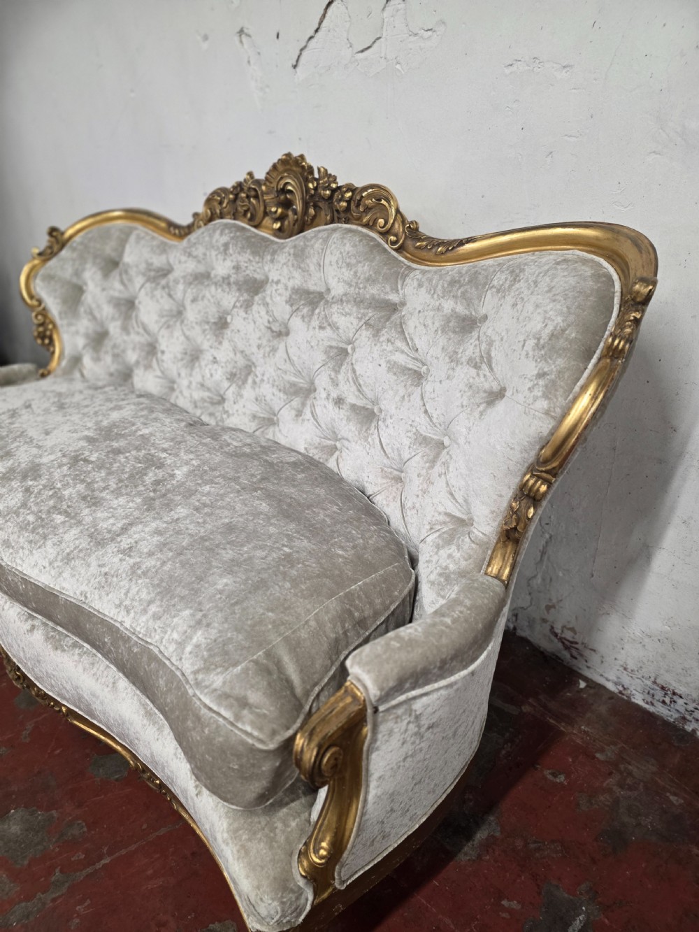 A late 19th-century Victorian Rococo Revival sofa with a carved gold giltwood frame, deep button-tufted light grey velvet backrest, and cabriole legs. View XII