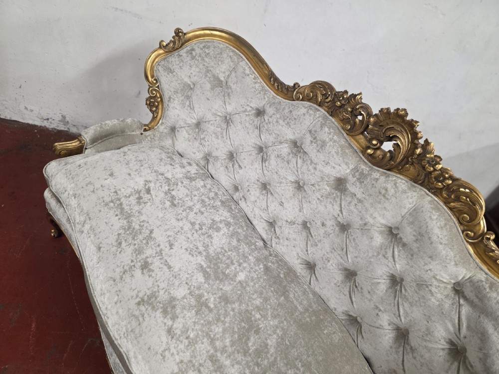 A late 19th-century Victorian Rococo Revival sofa with a carved gold giltwood frame, deep button-tufted light grey velvet backrest, and cabriole legs. View XIV