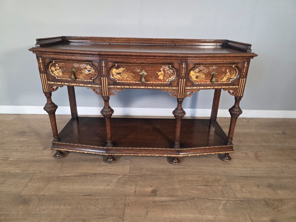 An antique solid oak console table featuring carved drawers, inlaid details, turned supports, and an undertier shelf. View II