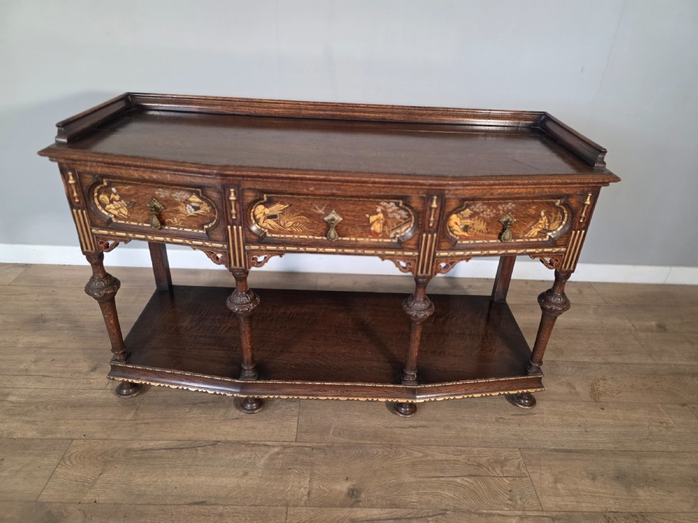 An antique solid oak console table featuring carved drawers, inlaid details, turned supports, and an undertier shelf. View III