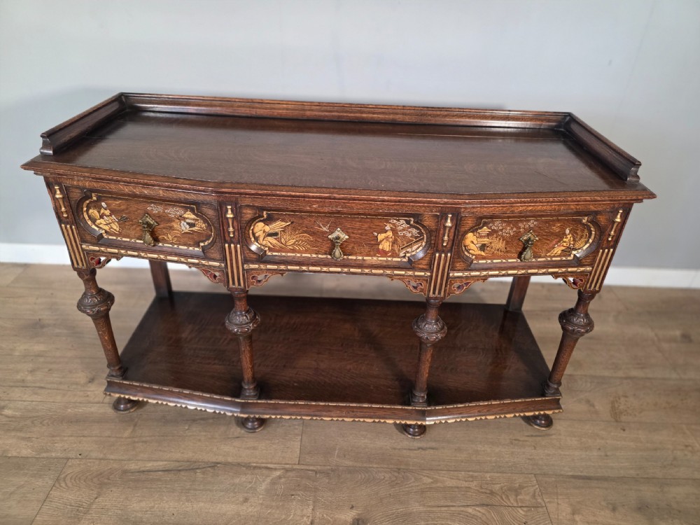 An antique solid oak console table featuring carved drawers, inlaid details, turned supports, and an undertier shelf. View IV