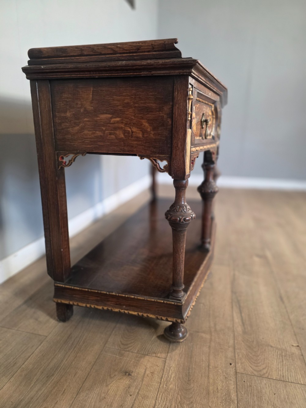An antique solid oak console table featuring carved drawers, inlaid details, turned supports, and an undertier shelf. View VIII
