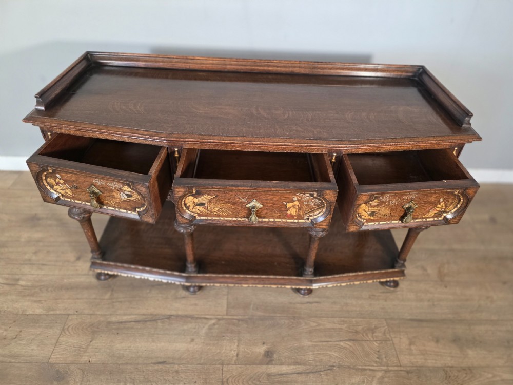 An antique solid oak console table featuring carved drawers, inlaid details, turned supports, and an undertier shelf. View XII