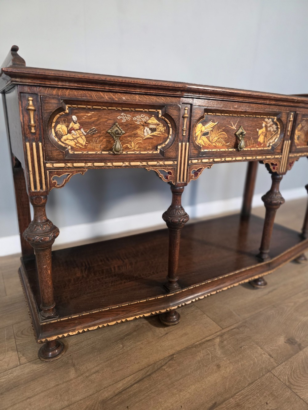 An antique solid oak console table featuring carved drawers, inlaid details, turned supports, and an undertier shelf. View XIV