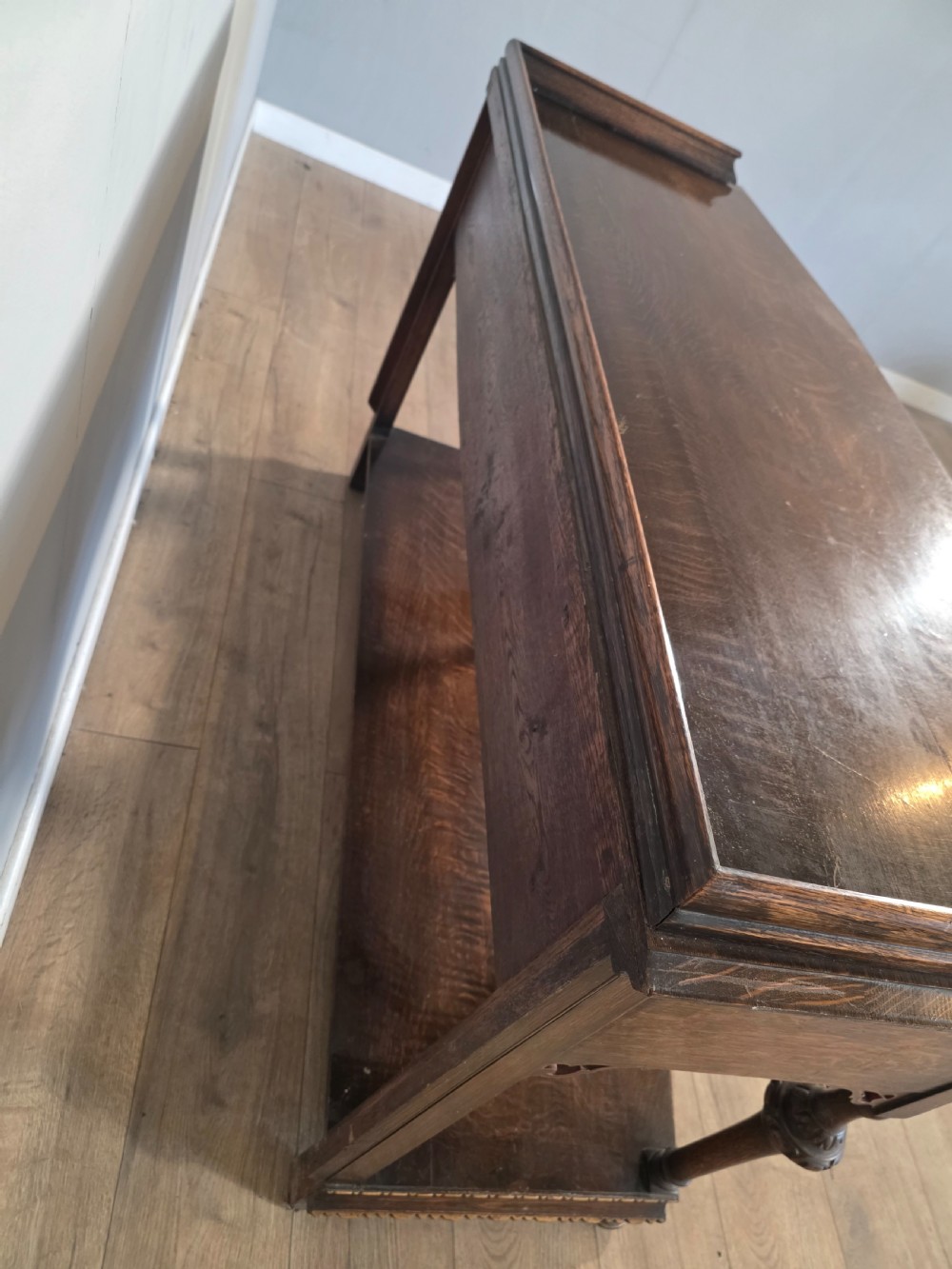 An antique solid oak console table featuring carved drawers, inlaid details, turned supports, and an undertier shelf. View XV