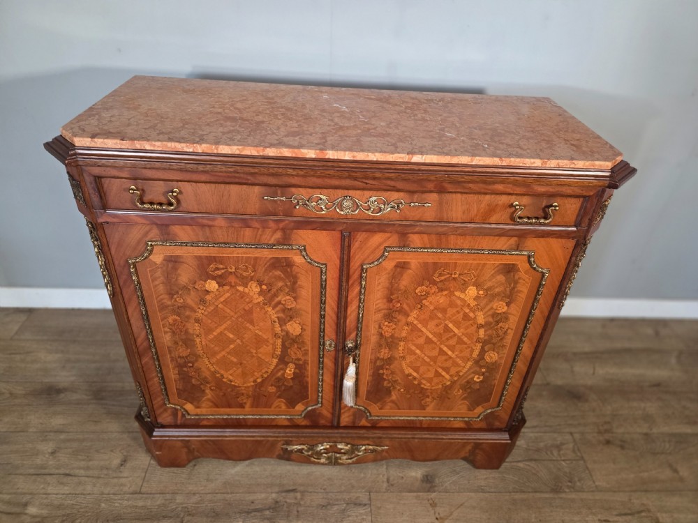 A 1920s French wooden cupboard featuring intricate floral marquetry inlay, gilt metal mounts, a single top drawer, two cabinet doors, and a reddish marble top surface. View III