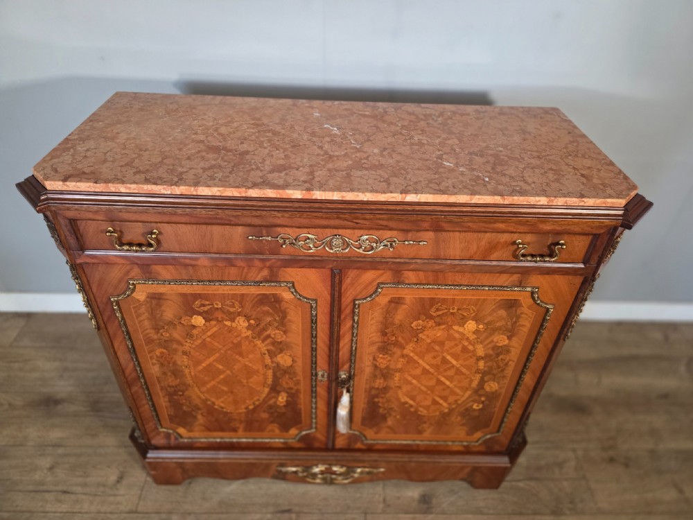 A 1920s French wooden cupboard featuring intricate floral marquetry inlay, gilt metal mounts, a single top drawer, two cabinet doors, and a reddish marble top surface. View IV