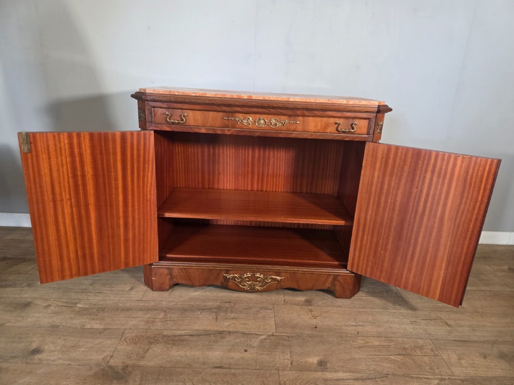 A 1920s French wooden cupboard featuring intricate floral marquetry inlay, gilt metal mounts, a single top drawer, two cabinet doors, and a reddish marble top surface. View VI