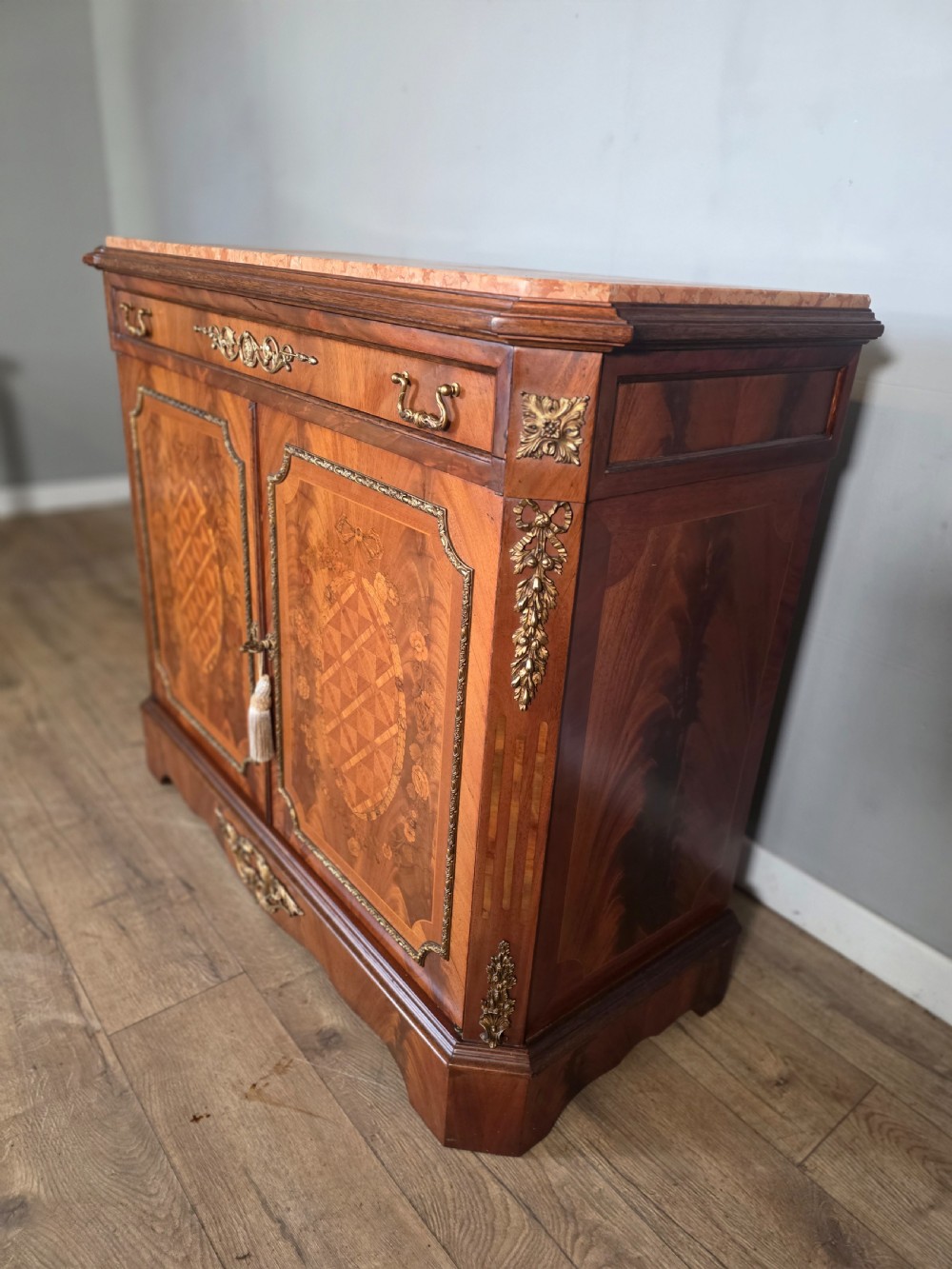 A 1920s French wooden cupboard featuring intricate floral marquetry inlay, gilt metal mounts, a single top drawer, two cabinet doors, and a reddish marble top surface. View VIII
