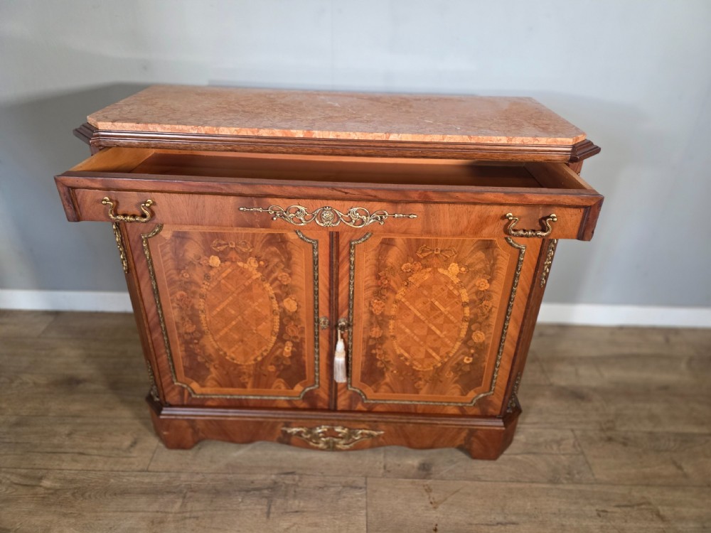 A 1920s French wooden cupboard featuring intricate floral marquetry inlay, gilt metal mounts, a single top drawer, two cabinet doors, and a reddish marble top surface. View X