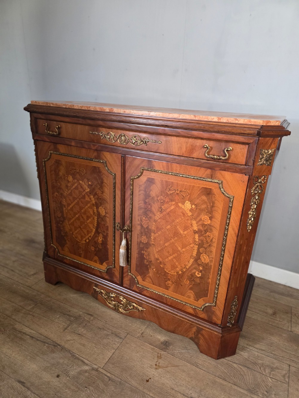 A 1920s French wooden cupboard featuring intricate floral marquetry inlay, gilt metal mounts, a single top drawer, two cabinet doors, and a reddish marble top surface. View XIII