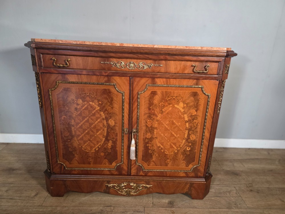 A 1920s French wooden cupboard featuring intricate floral marquetry inlay, gilt metal mounts, a single top drawer, two cabinet doors, and a reddish marble top surface. View XIV