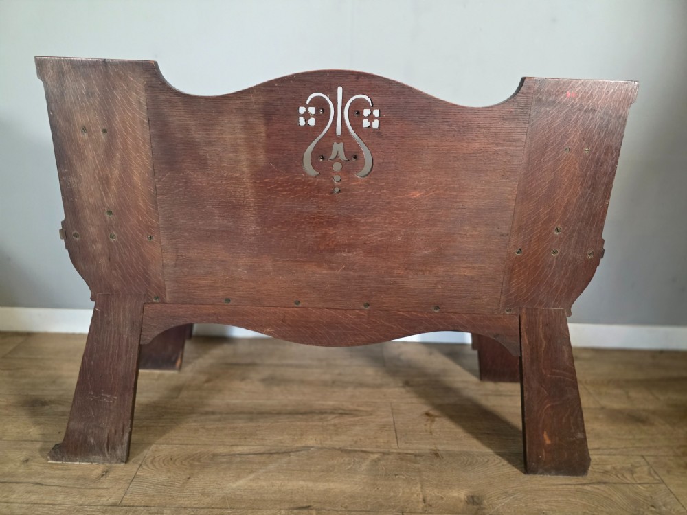 A dark oak Arts and Crafts hall bench featuring carved lion armrests, angled side legs, and a stylized inlaid motif on the backrest. View XI
