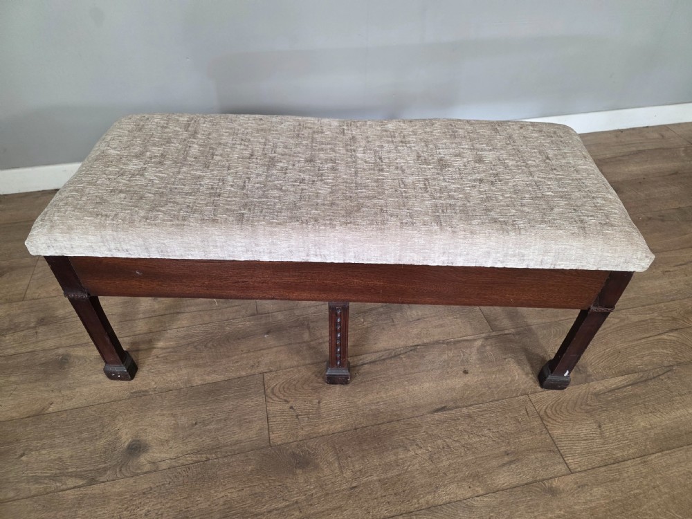 An 18th-century Adam style dark mahogany long window seat with six square tapered legs and a beige textured upholstered seat. View VIII