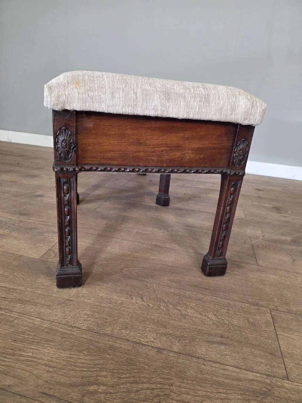 An 18th-century Adam style dark mahogany long window seat with six square tapered legs and a beige textured upholstered seat. View IX