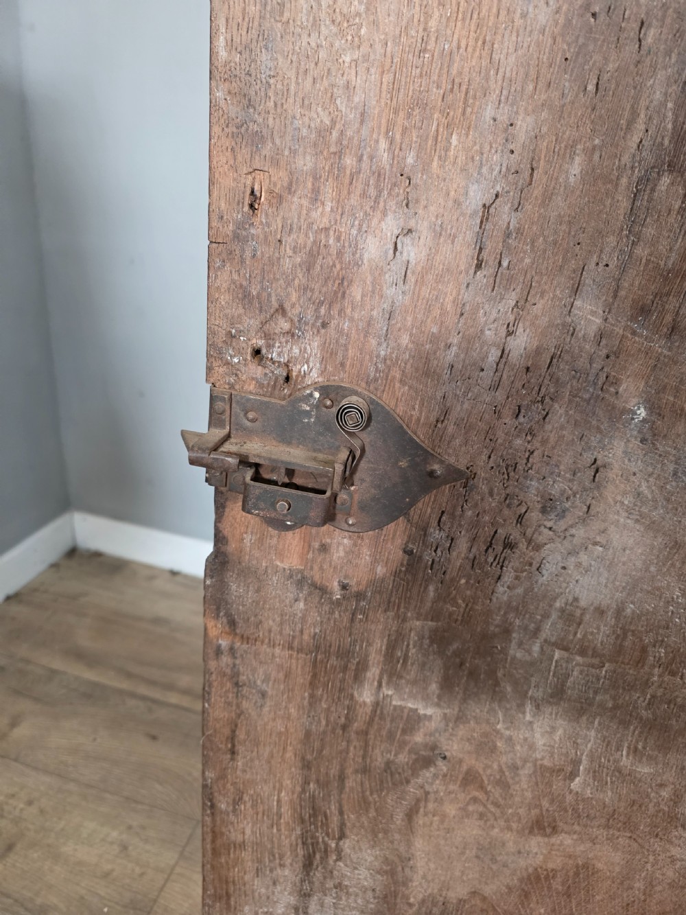 An 18th-century primitive dark oak cupboard featuring two panelled doors with notch carving, wrought iron escutcheons, and moulded top cornicing. View VI