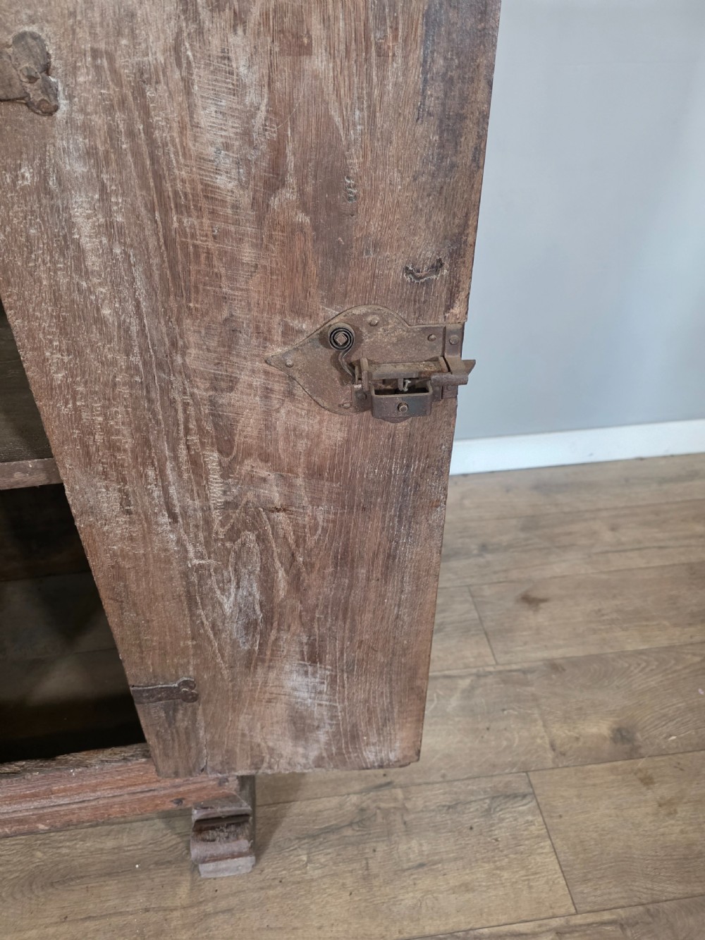 An 18th-century primitive dark oak cupboard featuring two panelled doors with notch carving, wrought iron escutcheons, and moulded top cornicing. View IX