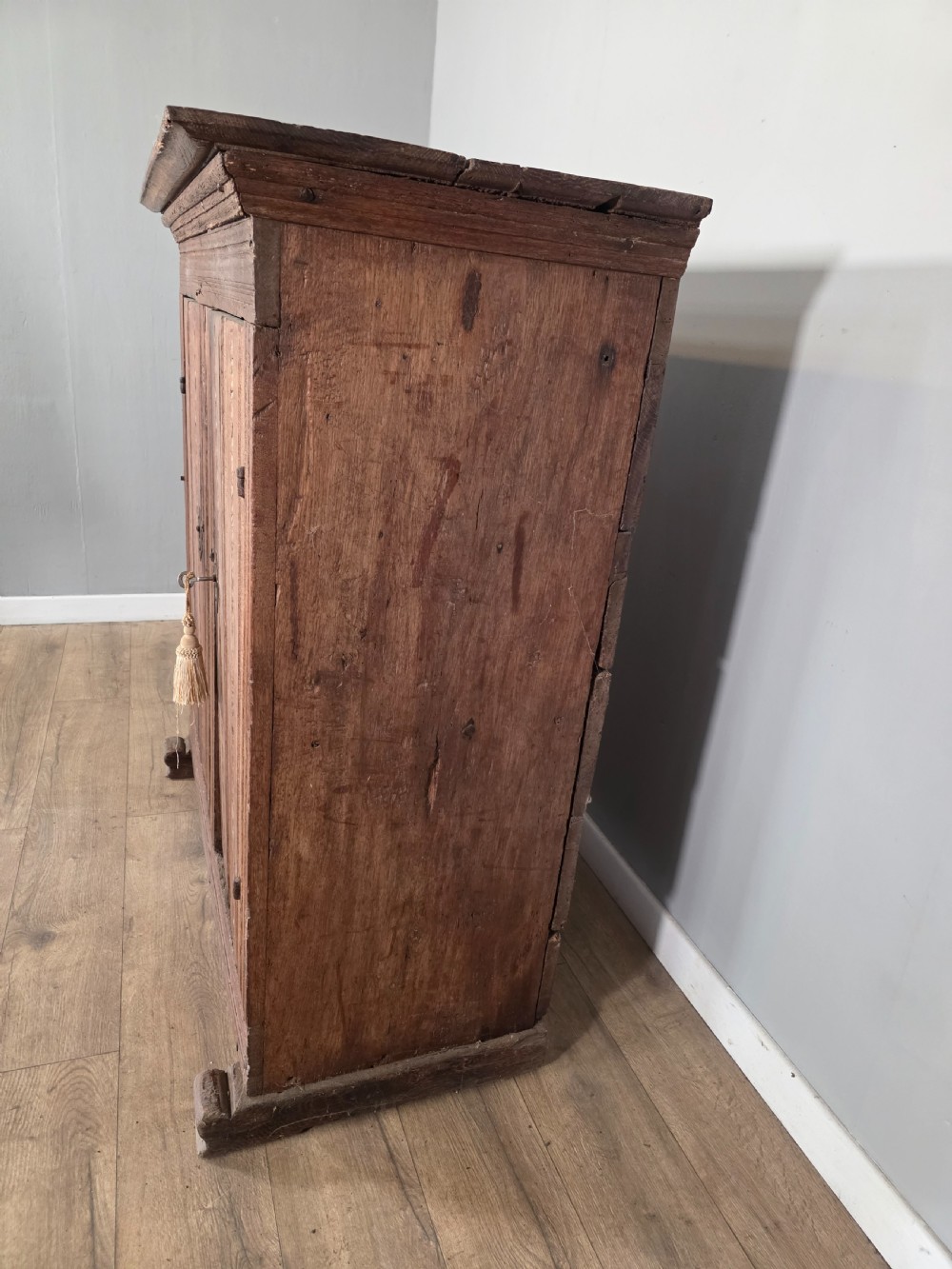 An 18th-century primitive dark oak cupboard featuring two panelled doors with notch carving, wrought iron escutcheons, and moulded top cornicing. View XIII