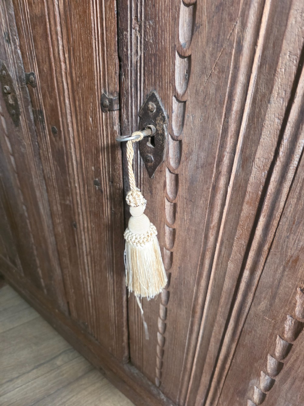 An 18th-century primitive dark oak cupboard featuring two panelled doors with notch carving, wrought iron escutcheons, and moulded top cornicing. View XVI
